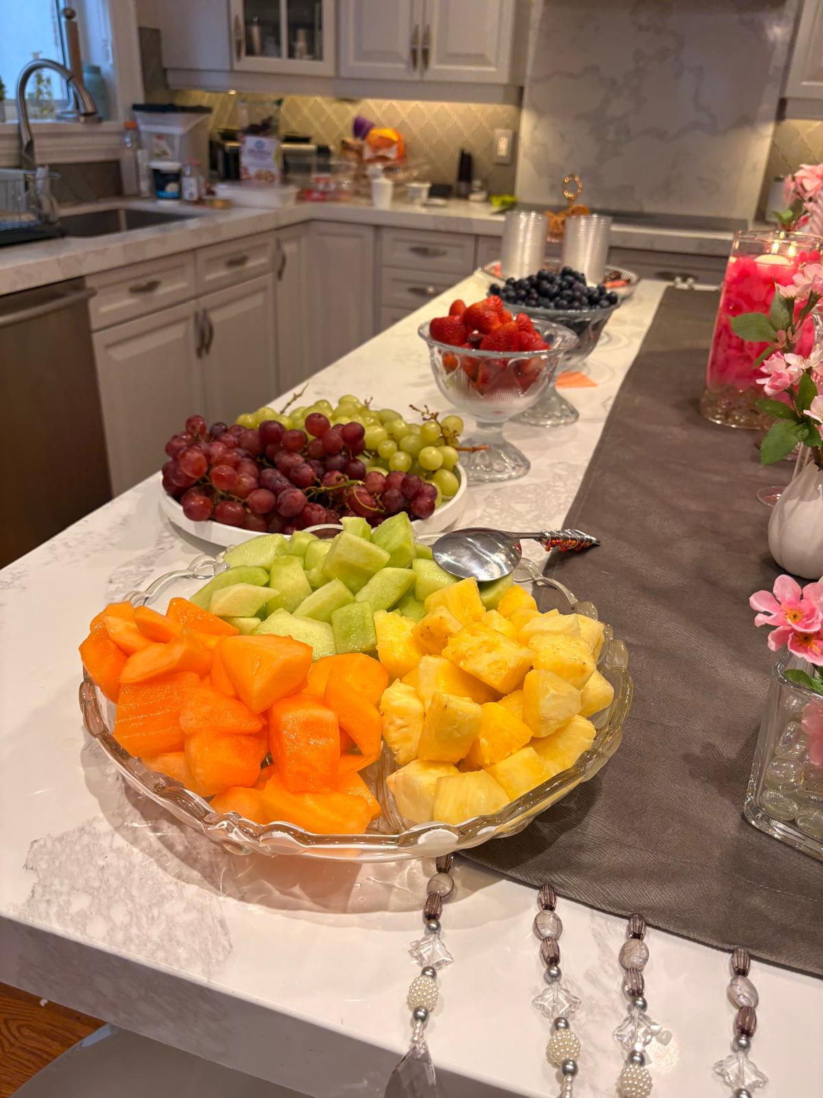 Platters of fresh fruit - melon, pineapple, grapes, strawberries, and blueberries