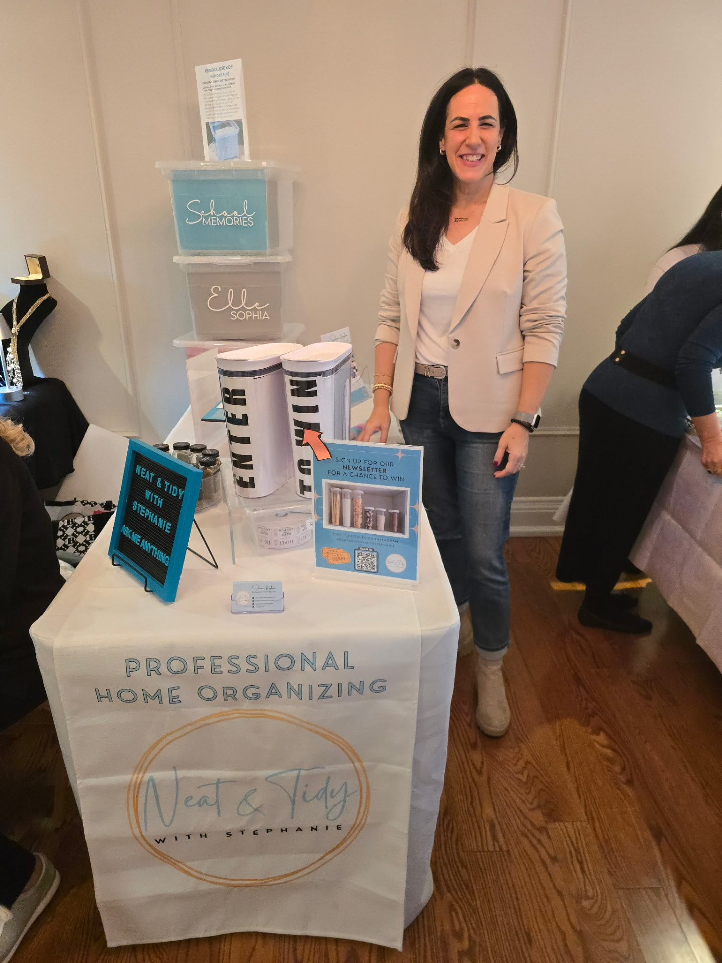 Vendor smiling beside her display of labelled storage bins and organiser containers