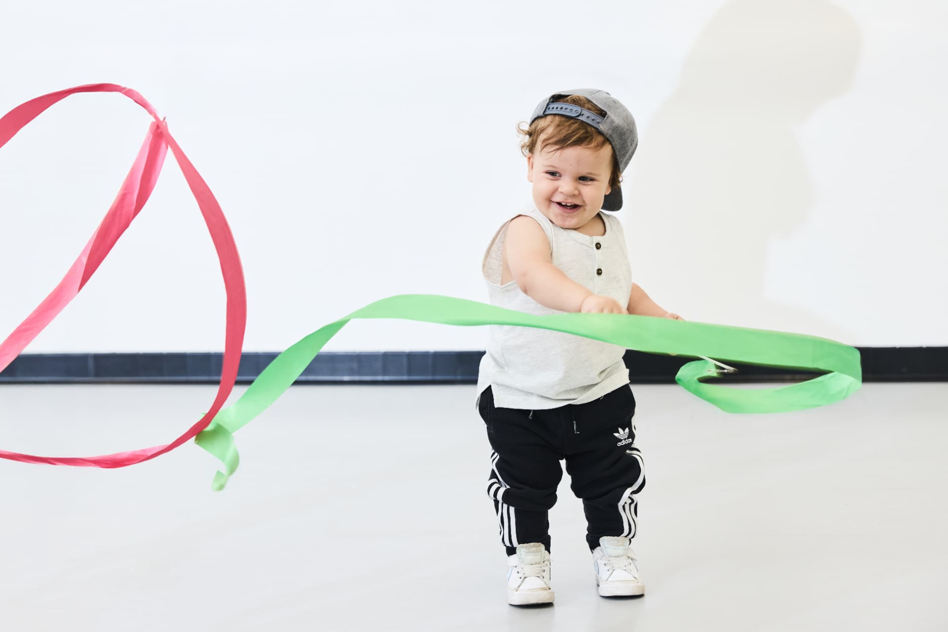 Smiling toddler playing with pink and green dance ribbons