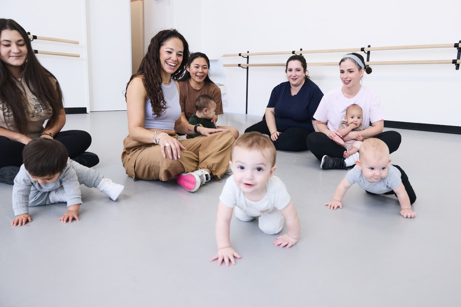 Moms sitting together as babies play on the studio floor