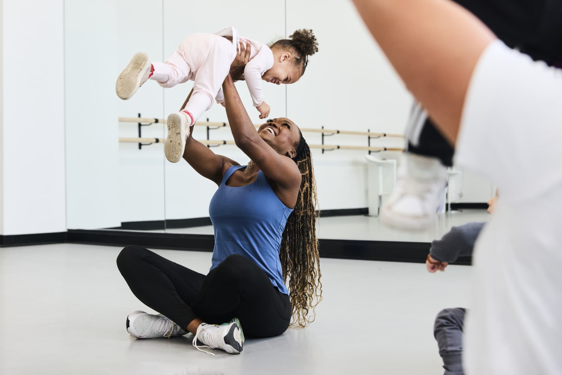 Mom sitting on the studio floor lifting her smiling baby