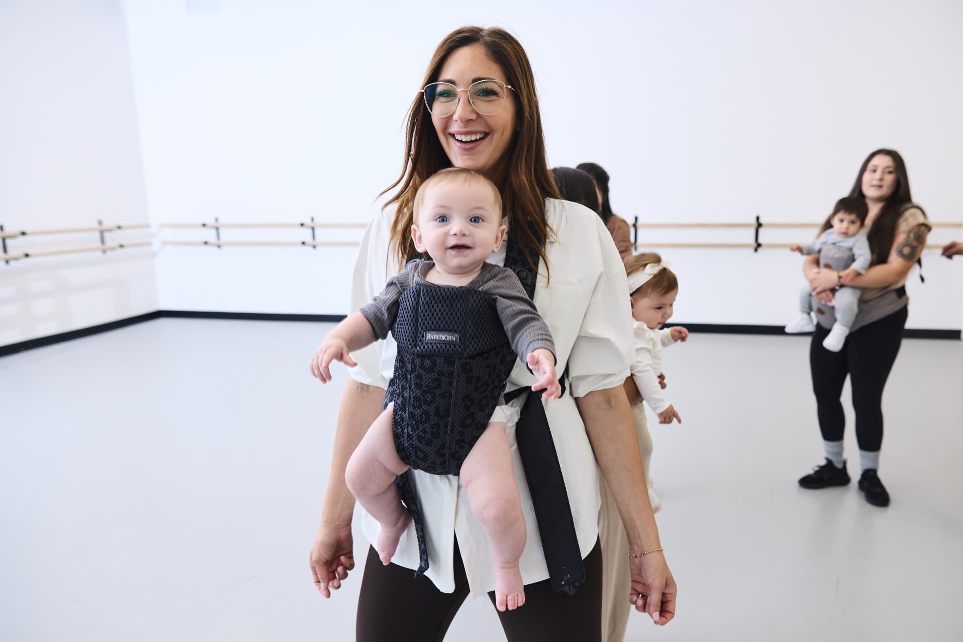 Smiling mom dancing with her baby in a carrier