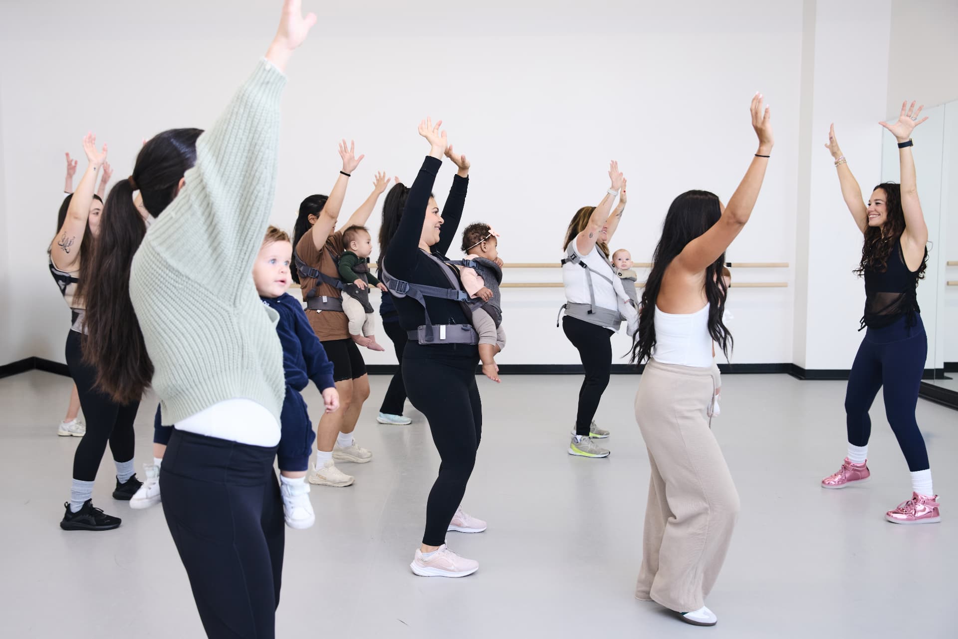 Moms stretching their arms overhead during dance class